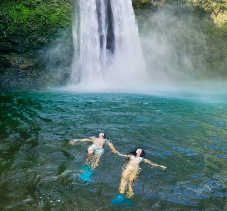 A couple enjoys the water near a waterfall during their honeymoon in Kauaʻi.