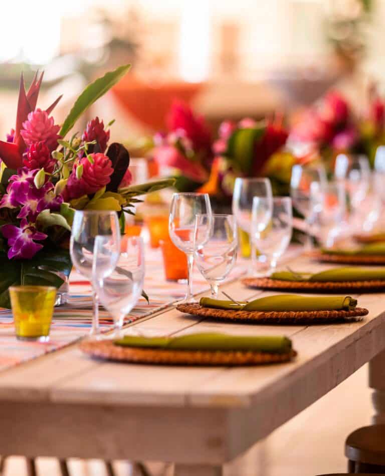 A beautifully arranged table featuring colorful flowers and elegant place settings, set for a Kauaʻi wedding celebration.