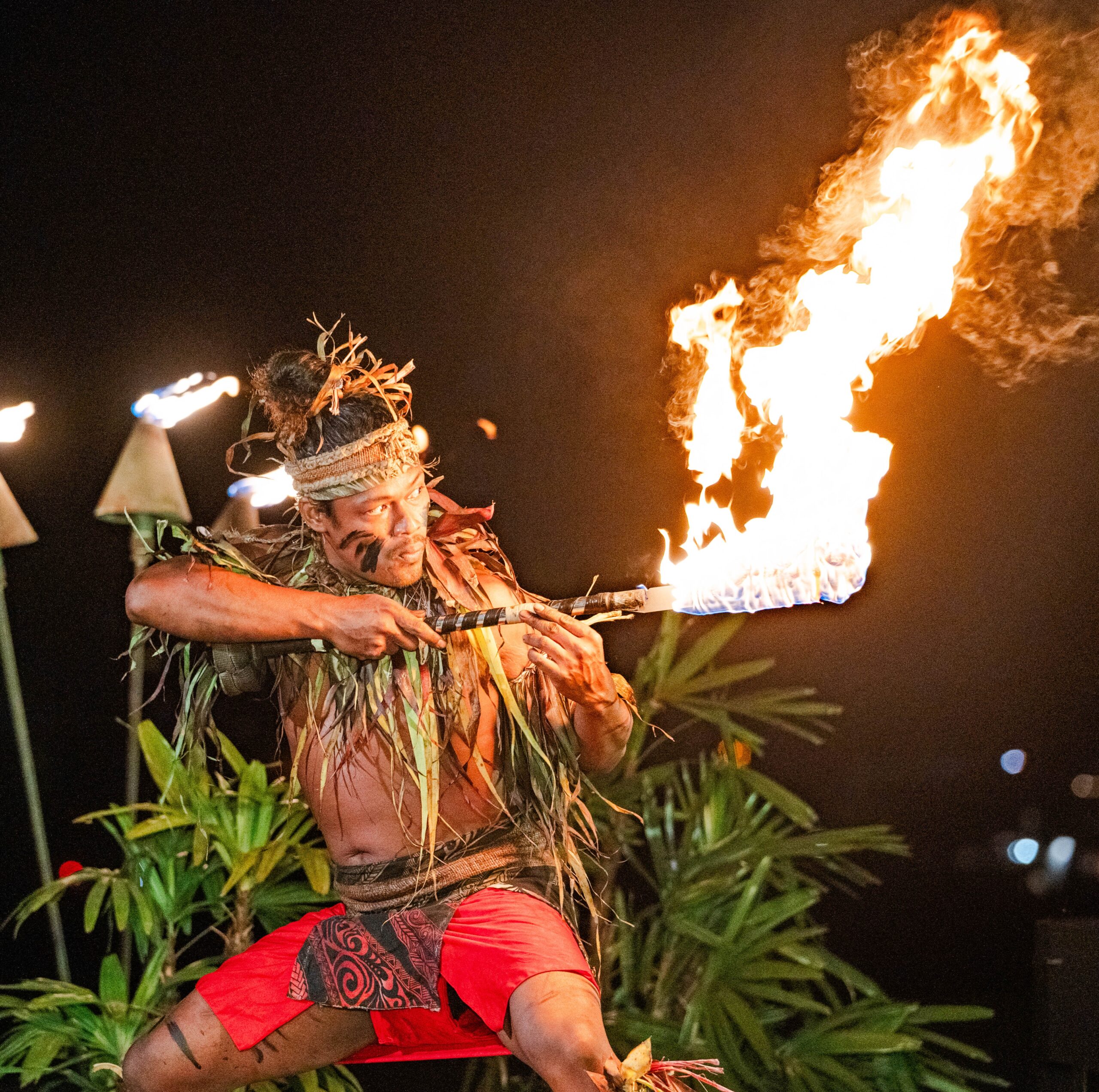 A man in traditional Hawaiian costume performs a captivating fire dance, showcasing cultural heritage and artistry.