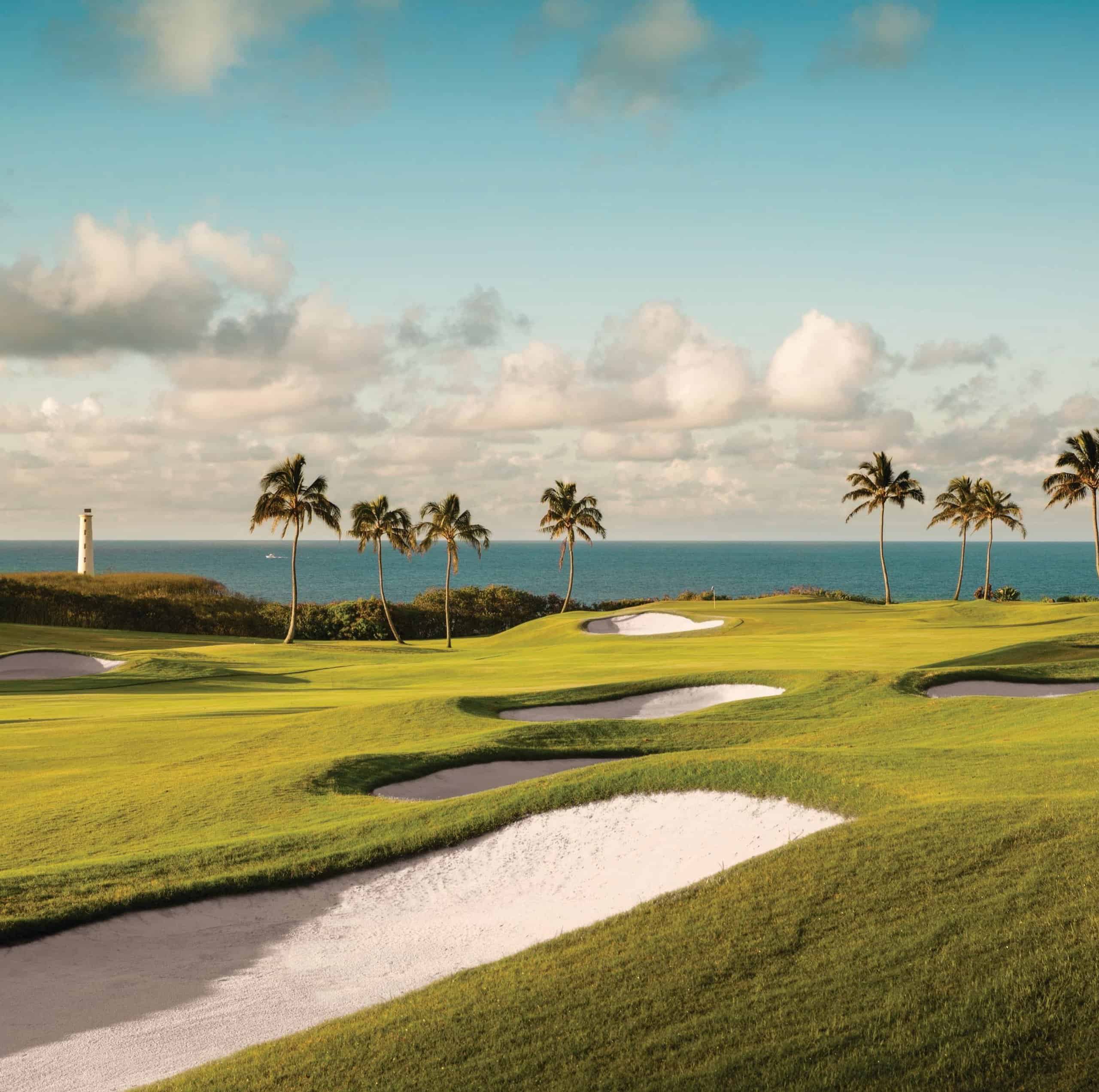 A scenic view of the golf course at The Royal Sonesta Kauai Resort, with vibrant greens and palm trees under a clear blue sky.