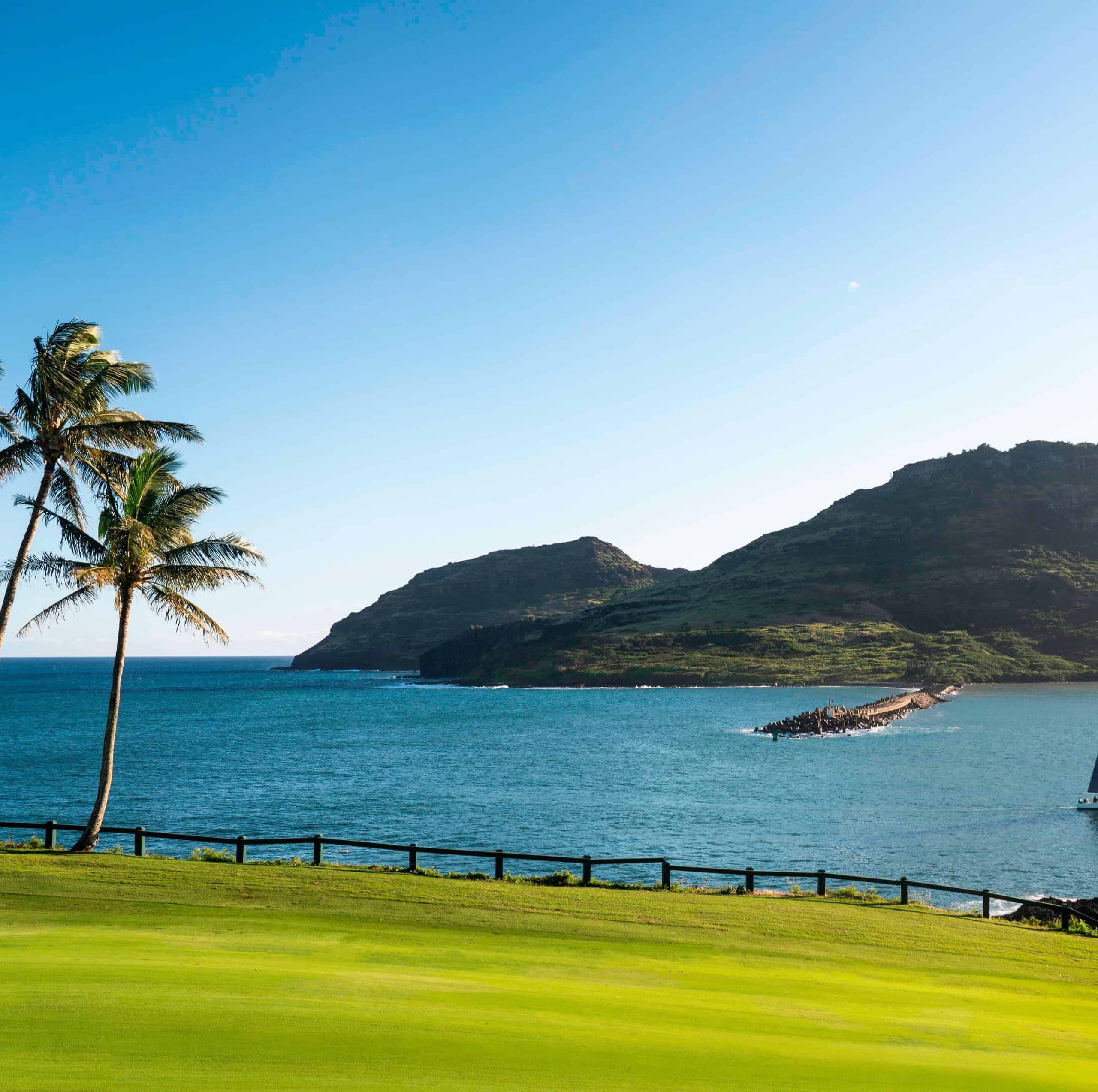 Scenic view of the Kauai resort golf course, featuring lush greens and distant mountains under a clear blue sky.